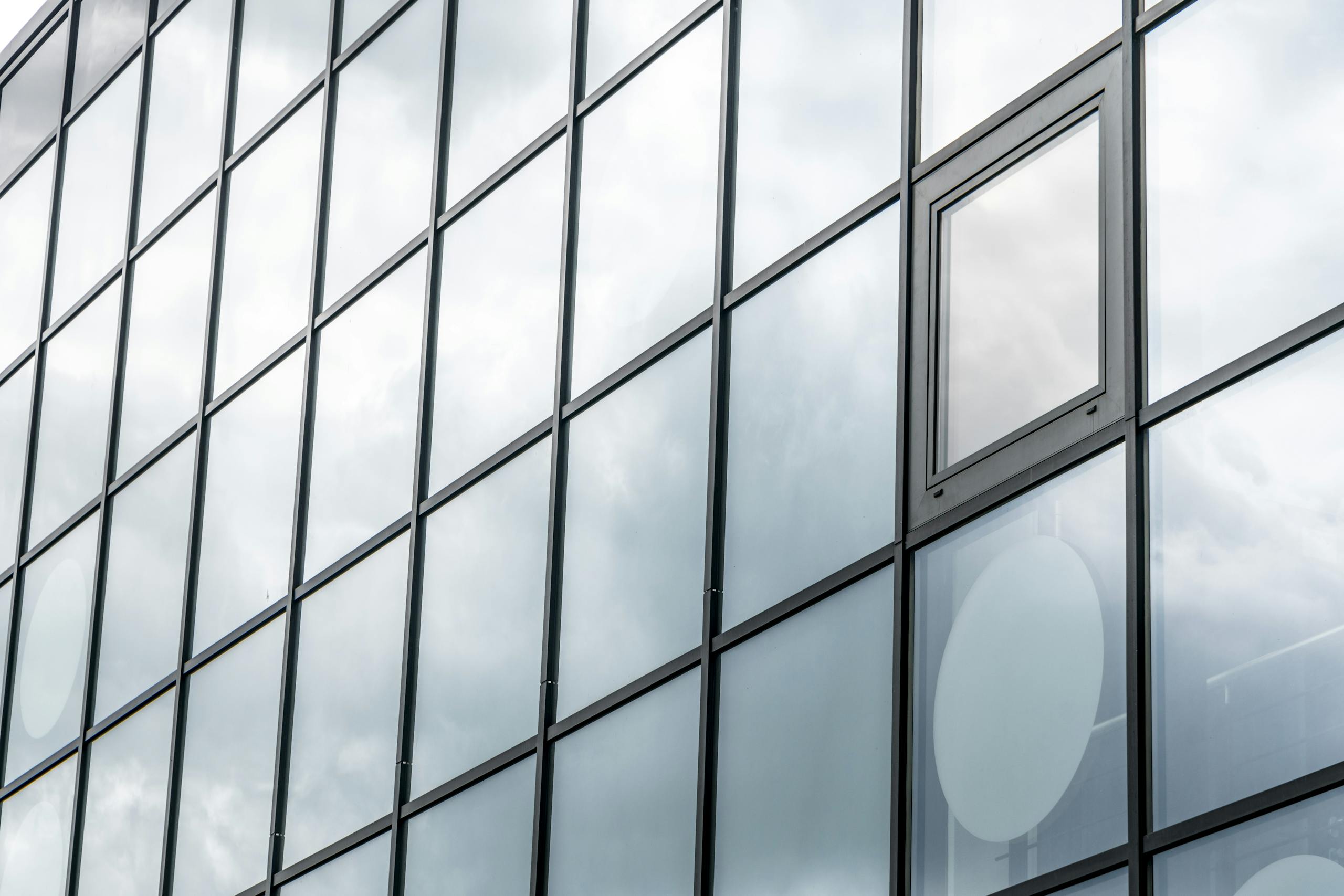 A modern glass facade reflecting a cloudy sky, showcasing contemporary architecture.